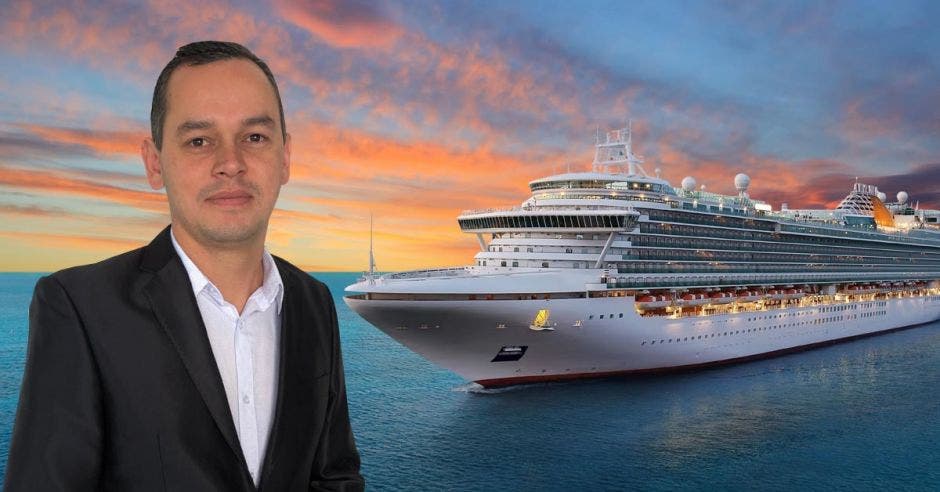 Un hombre con saco y corbata frente a la imagen de un crucero