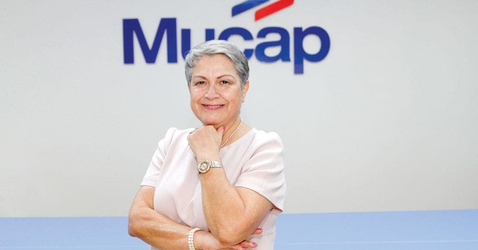 Mujer posa frente a logo de Mucap