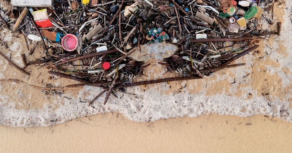 Una ola arrastrando basura en la costa