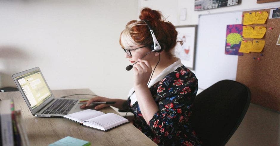 Una mujer con una computadora y audífonos