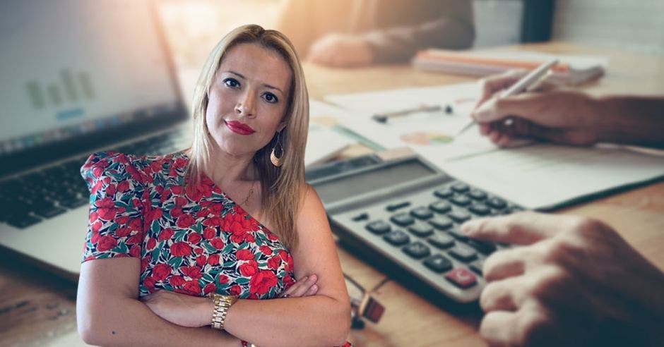 Una mujer con blusa floreada posa junto a una calculadora