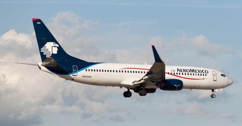 Un avión blanco con ribetes rojos en una pista de aterrizaje