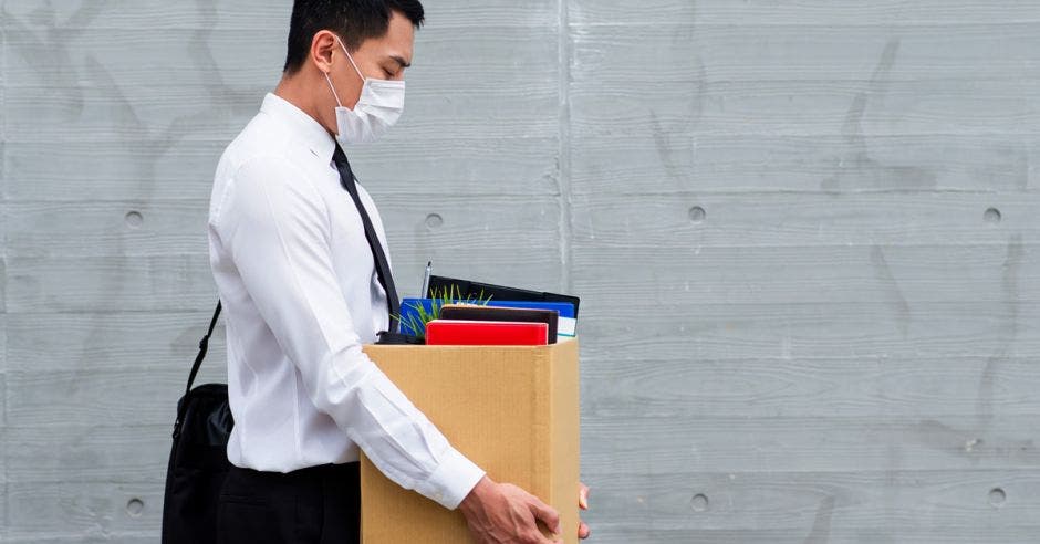 Un hombre con mascarilla recoge una caja de su oficina