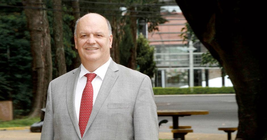 un hombre calvo con corbata roja y traje gris