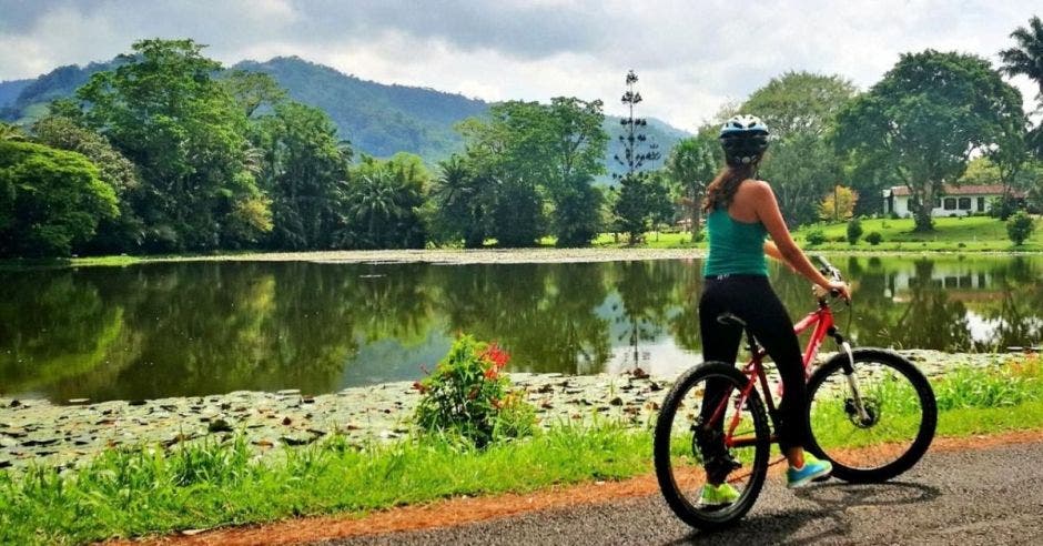 Una mujer en bicicleta mira un lago