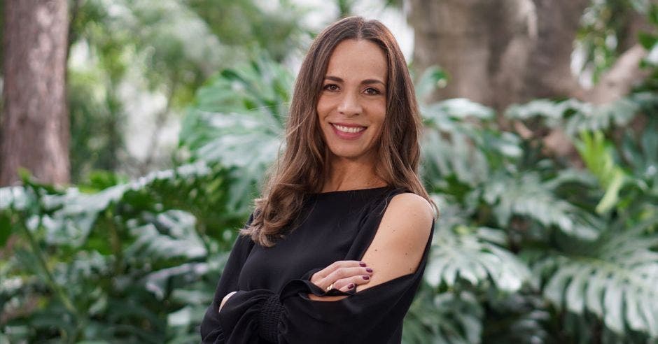 Una mujer de traje negro sobre un fondo de plantas verdes