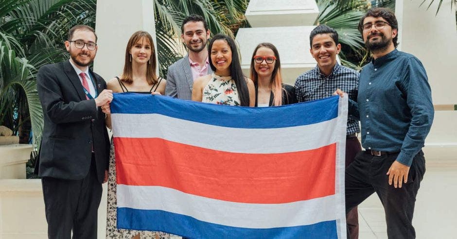 un grupo de siete personas sostiene la bandera de Costa Rica