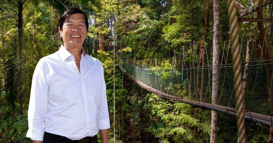 Un hombre asiático de camisa blanca sobr eun puente colgante