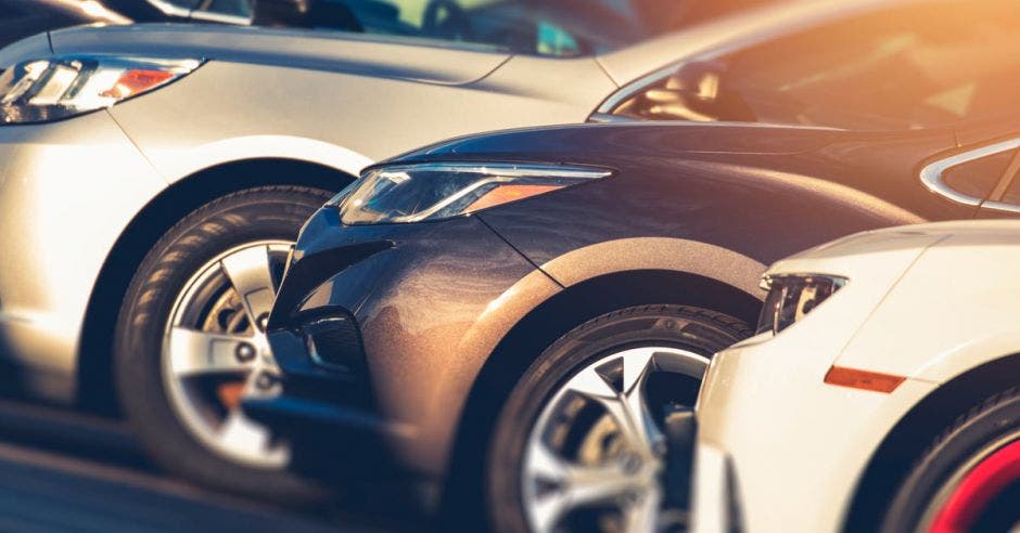 Una serie de carros puestos en fila, uno blanco, otro negro y otro gris