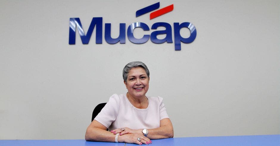 Mujer sentada con logo de Mucap de fondo