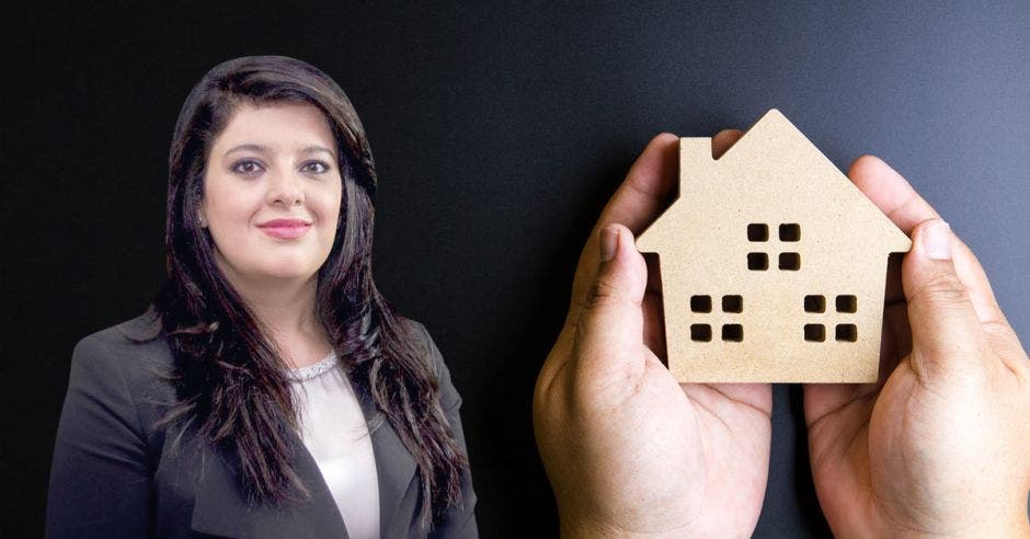 Mujer frente a mano sosteniendo imagen de vivienda