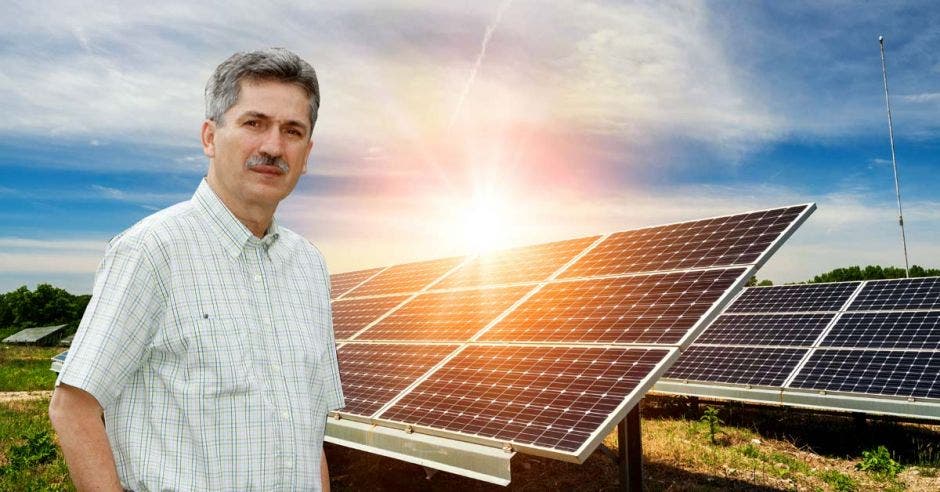 un hombre de bigote y camisa blanca posa sobre un fondo de paneles solares