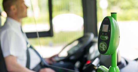 conductor de autobus de fondo y dispostivo de pago electrónico en primer plano
