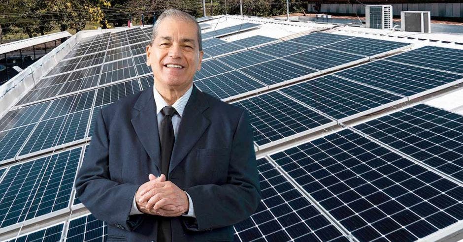 Un hombre sonriente frente a un conjunto de paneles solares