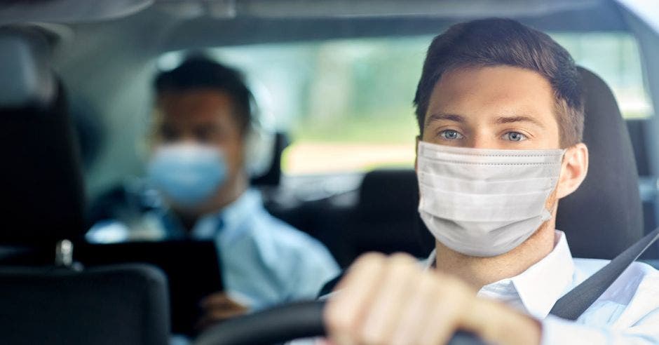 un hombre con mascarilla conduce un vehículo