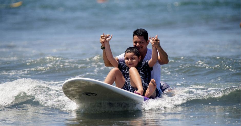 un padre con su hijo en una tabla de surf