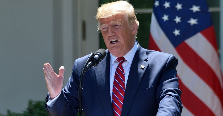 un hombre de pelo rubio con saco azul, corbata roja y camisa blanca