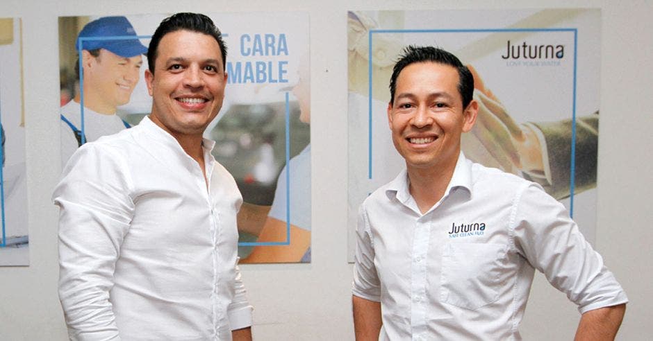 un hombre alto de camisa blanca junto a otro hombre de menor estatura, también con camisa blanca