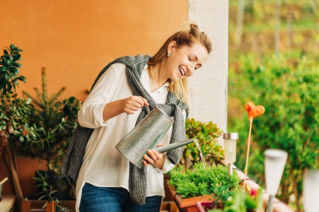 Una muchacha cuida las plantas de su hogar