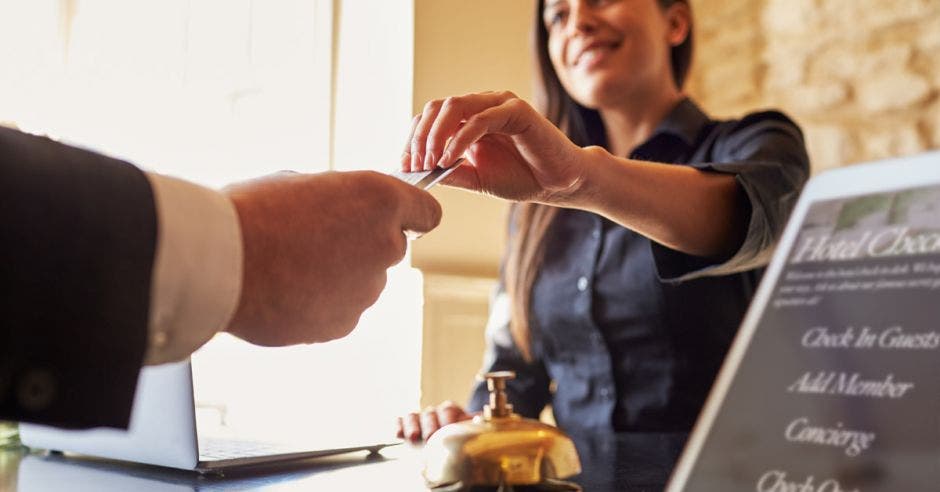 Una mujer entrega una llave a un cliente en un hotel