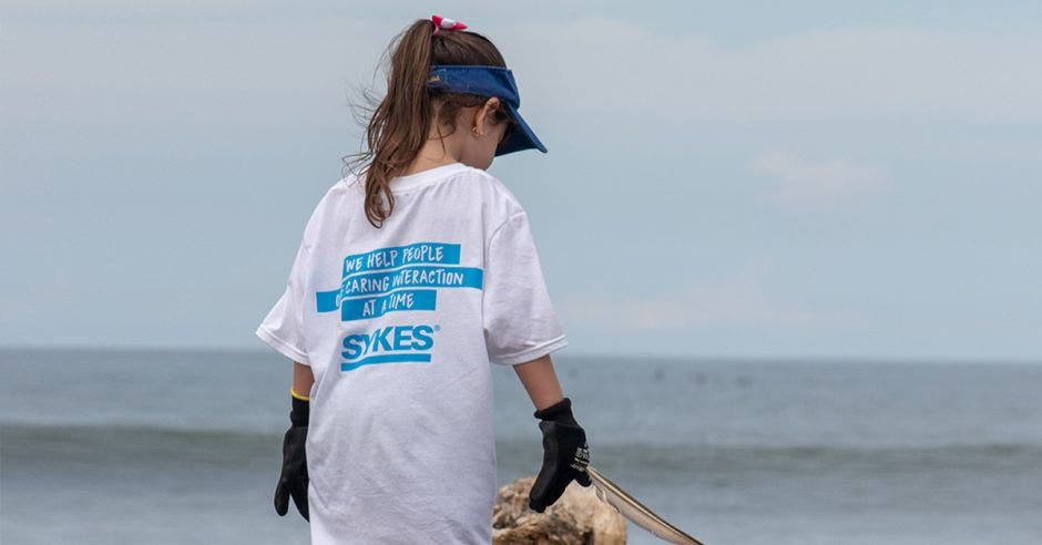 Un niña recoge basura en la playa