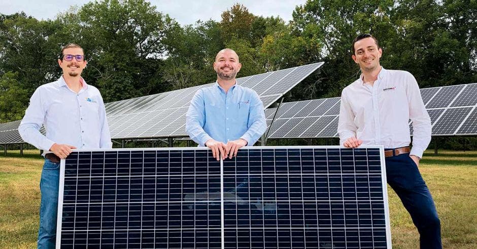 tres hombres posan junto a un panel solar