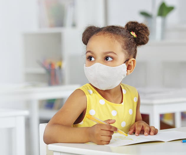 Una niña con mascarilla estudiando