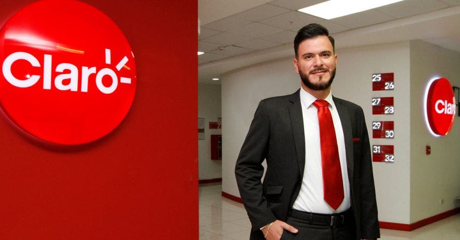 un hombre joven con barba vestido con traje negro y corbata roja