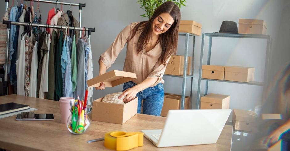 Joven empresaria guardando ropa en una caja