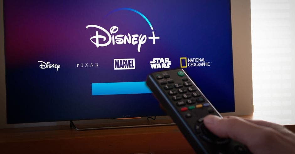 Disney+ en televisor y mano con control cambiando canal