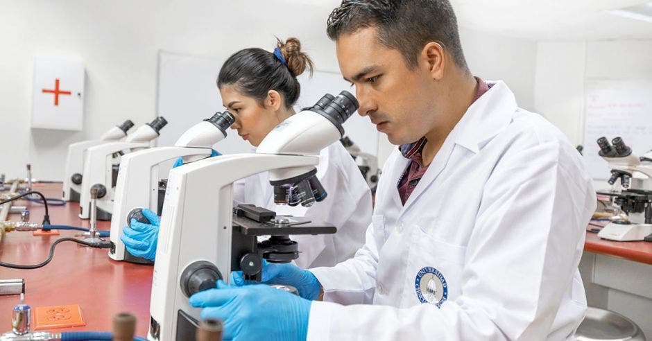 Dos estudiantes de UCIMED viendo un microscopio