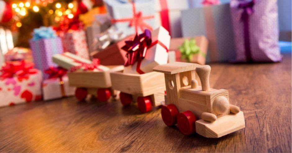 trenecito de madera con ruedas rojas y de fondo regalos de navidad