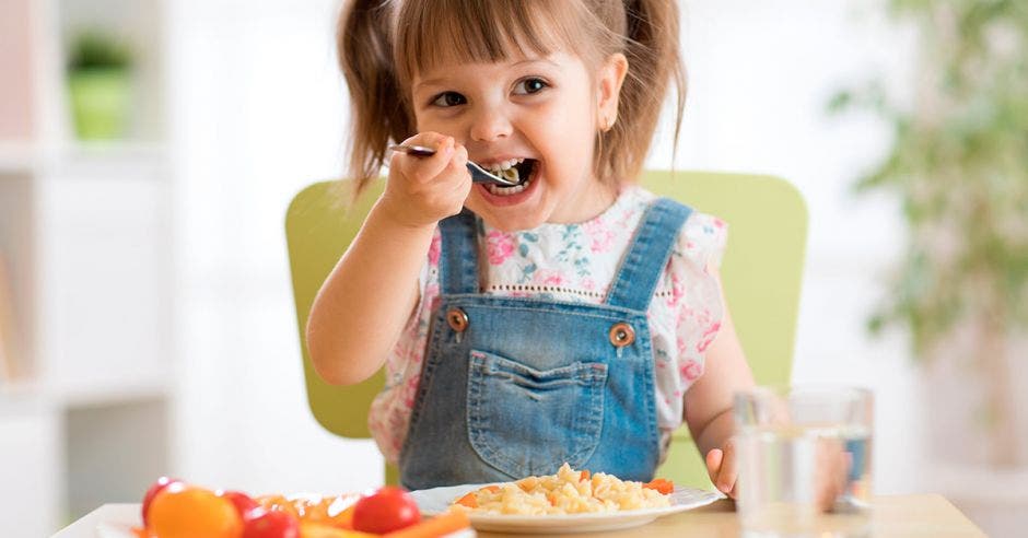 Una niña con una cuchara sentada comiendo