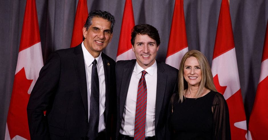 Personas de traje frente a bandera de Canadá