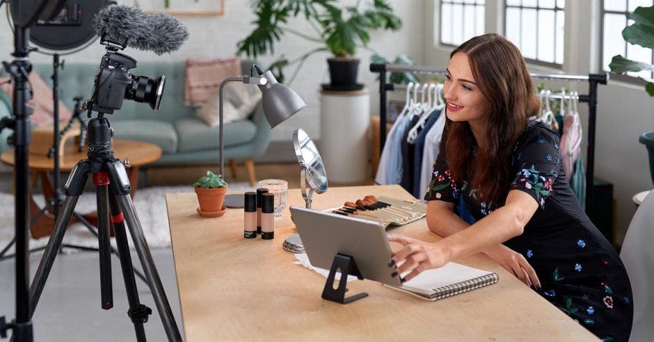 mujer sentada frente a una laptop y cámara de video