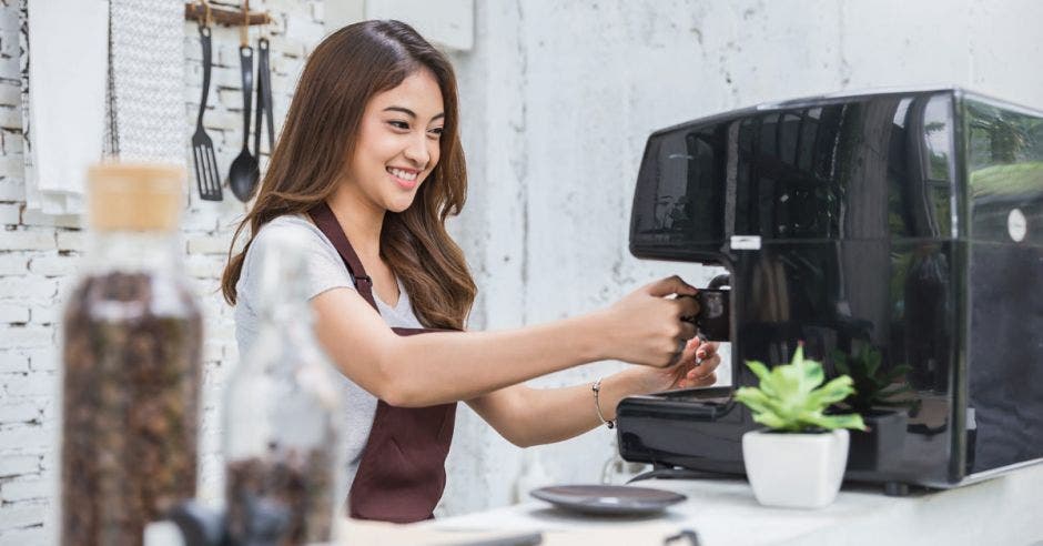 mujer con mandil marrón preparando un café