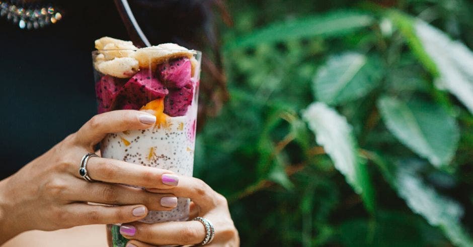 una mujer toma un batido de frutas en medio de la naturaleza