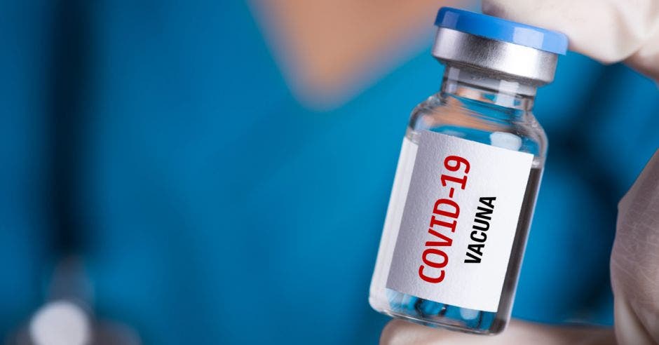 Una persona con gabacha sosteniendo una dosis de vacuna contra Covid-19