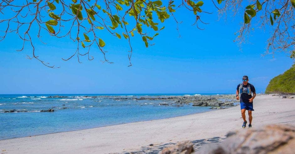 un hombre de estatura mediana corre por la arena en la playa