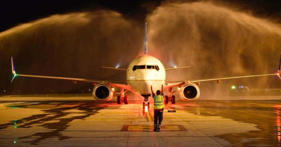 un avión aterrizando en un aeropuerto siendo roceado por agua