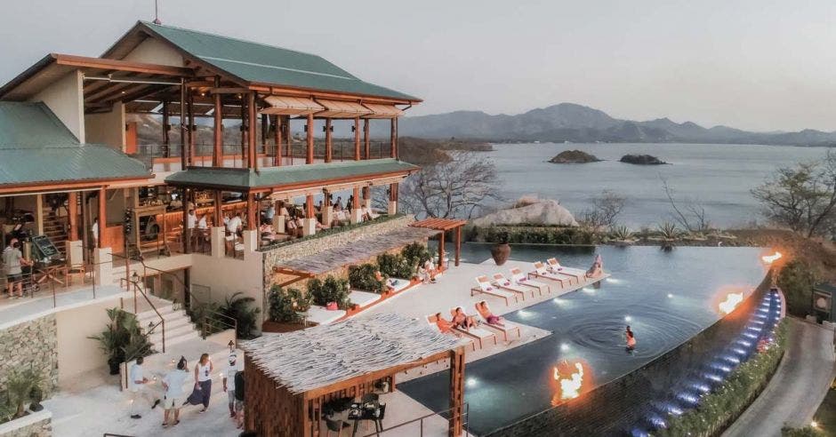 imagen de un hotel de playa de noche. Tiene piscina infinita.