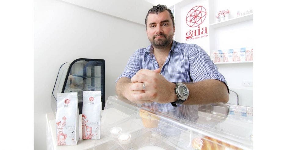 señor de barba con camisa azul atrás de un mostrador de vidrio