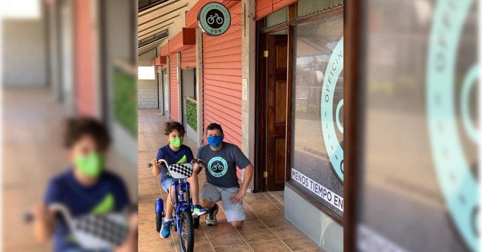 Un niño en triciclo junto a un hombre de cuclillas