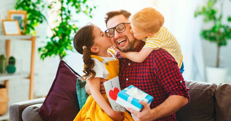 un papá con sus dos hijos abriendo un regalo del Día del Padre