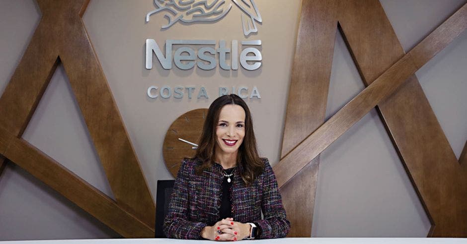 una mujer de traje entero con vista de frente y debajo de un letrero que dice Nestlé