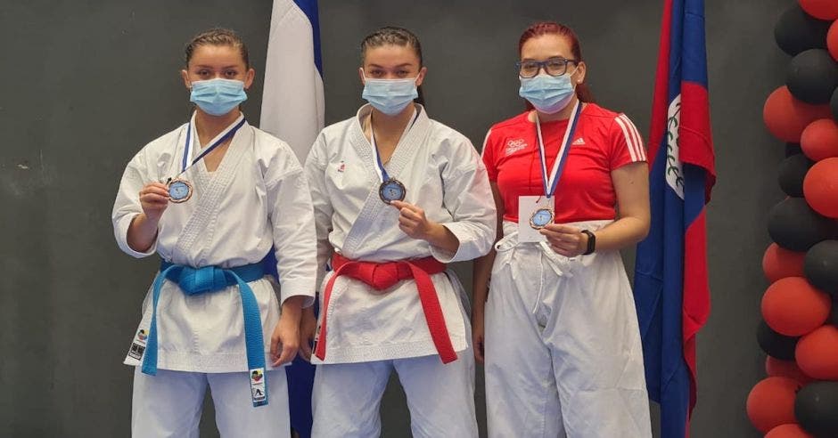tres karatecas mostrando sus medallas