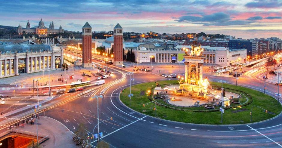 una ciudad iluminada, con un monumento dorado en el centro de una plaza