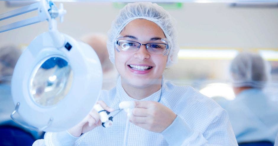 una mujer con bata blanca y anteojos sonrie