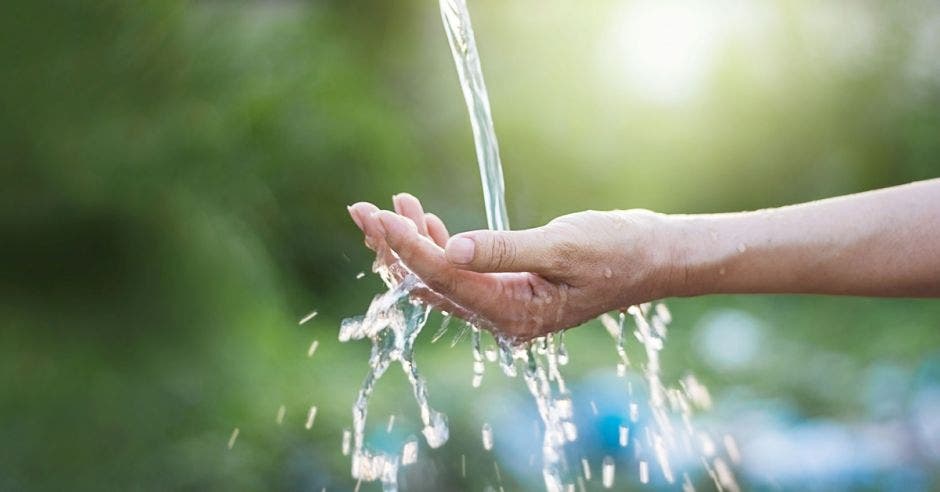 una mano recoge agua de un riachuelo