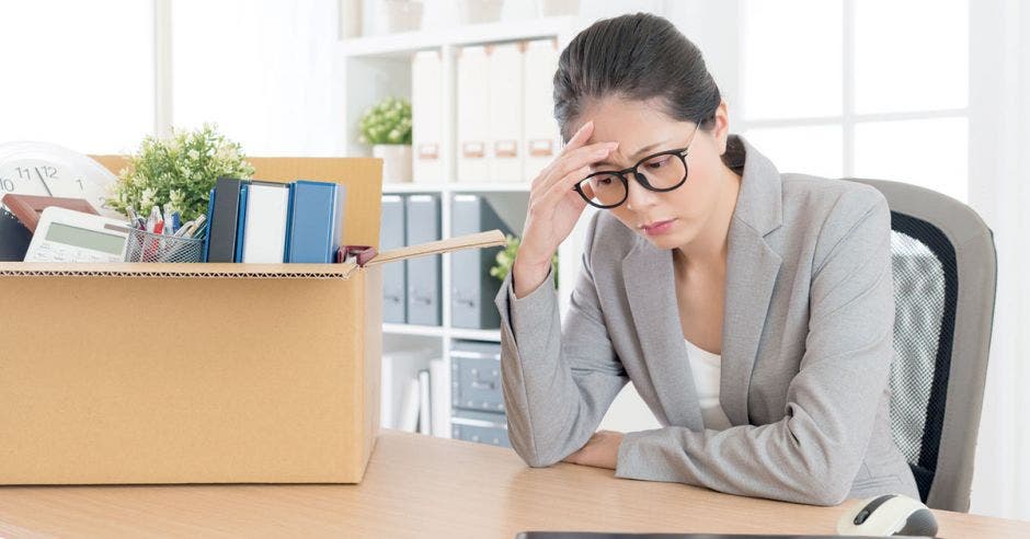 Mujer de gris triste con caja con sus cosas